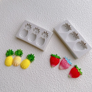 Detailed view of pineapple and strawberry silicone molds with finished fruit shapes