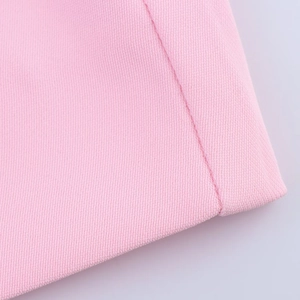 Gros plan sur le blazer rose montrant la texture du tissu sergé et les coutures détaillées