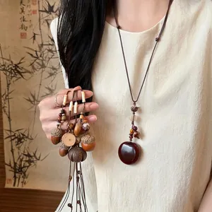 Artisan woven rope necklace with natural acorn and wood beads on a bamboo screen backdrop