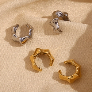 Polished 18K gold and silver bamboo wave ear cuffs set on elegant satin background