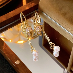 Detail of elegant gold tassel earrings with pink beads and pearls in a luxury jewelry box