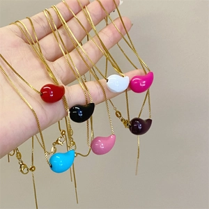 Close-up of multicolored bean pendants on gold chains held in a radial arrangement