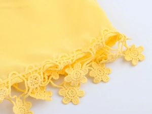 Close-up of delicate yellow lace trim with flower pendant details on a V-neck maxi dress