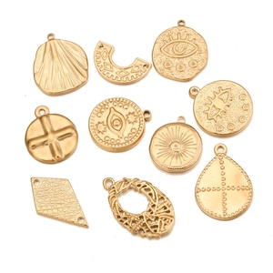 Macro view of gold stainless steel geometric pendants with vintage sun and eye engravings