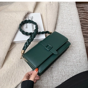 Detail of dark green crossbody bag with belt buckle and stylish woven shoulder strap