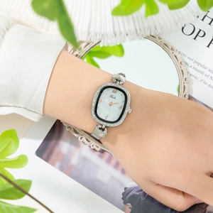 Elegant silver women's watch with oval shell dial and crystal-encrusted bezel on wrist