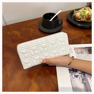 White long quilted wallet for women with golden zipper shown in a lifestyle cafe setting