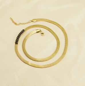Close-up of gold plated snake bone chain necklace with black gemstone inlay on silk