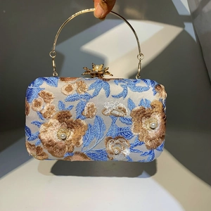 Close-up of floral embroidery with beads and pearls on an elegant blue evening handbag