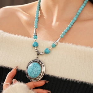 Detail of bohemian turquoise beaded necklace with large round stone pendant and vintage silver