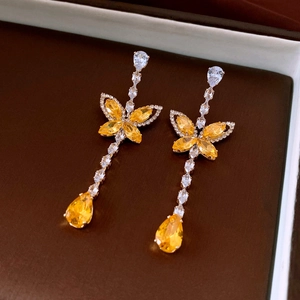 Détail de boucles d'oreilles papillon en zircon avec pierres jaunes en forme de poire