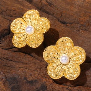 Textured gold petal earrings with center pearl inlay on a rustic wood background