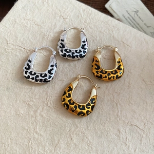 Close-up of gold and silver leopard print hoop earrings set on textured paper