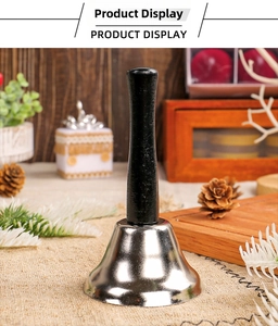 Close-up of polished silver hand bell with black handle on festive Christmas table