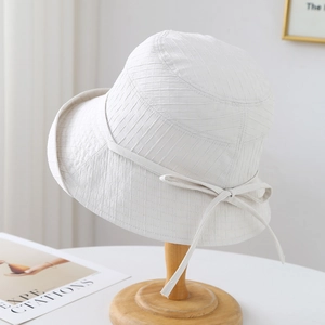 Gros plan sur un chapeau de soleil blanc matelassé avec nœud et texture quadrillée