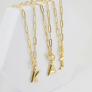 Detail of 18K gold-plated OT toggle necklaces with three-dimensional alphabet pendants