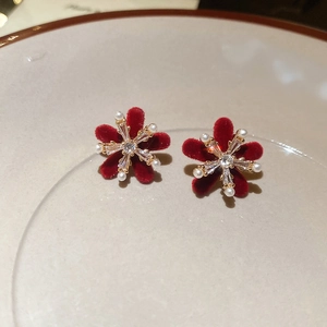 Macro view of velvet floral earrings with crystals and pearls on a ceramic plate