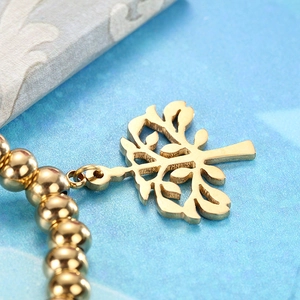 Vue détaillée du bracelet à perles dorées avec un pendentif symbole de l'arbre de vie