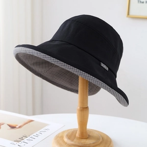 Détail d'un chapeau de soleil noir avec doublure à carreaux gris sur un support