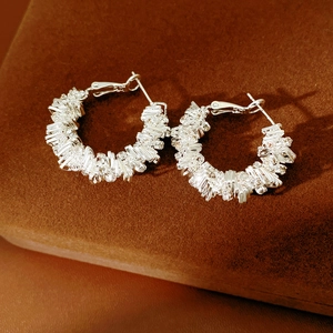 Close-up of silver geometric hoop earrings with sparkling rhinestones on brown velvet