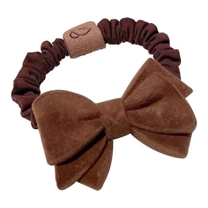 Dark brown bow hair scrunchie with plush fabric and elastic velvet texture on white background