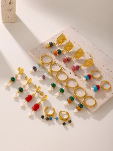 Collection of gold geometric earrings with colorful natural stones and pearls on stone base