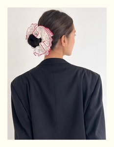 Détail d'un chouchou floral avec liseré rouge porté en chignon pour le coiffage