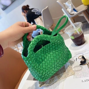 Handcrafted vibrant green woven bucket bag with thick strap handle in a cafe setting