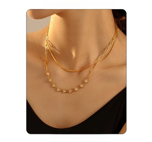 Detail of double-layered gold necklace with heart zircons and paperclip chain on model