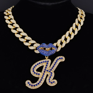 Gold-plated Cuban necklace with iced-out blue lips and letter K pendant on a black bust