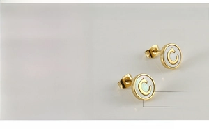 Detail of 10mm titanium steel earrings with 18K gold plating and shell inlay featuring letter C