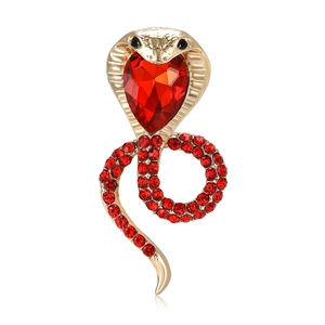 Golden snake brooch with red rhinestones and heart-shaped crystal on white background