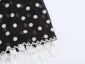 Détail du tissu noir à pois avec bordure en dentelle blanche et broderie florale