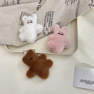 Close-up of soft plush bear charms in white, pink, and brown with metal chains