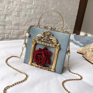 Close-up of golden baroque frame with red 3D rose detail on blue flower box bag