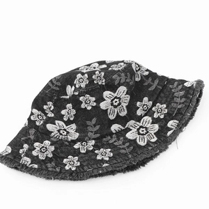 Detail view of denim bucket hat featuring white floral embroidery and frayed raw edges