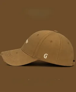 Close-up of distressed brown baseball cap with embroidered letter G and frayed brim edge