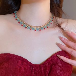 Detailed close-up of beaded choker necklace with red and turquoise accents on a model