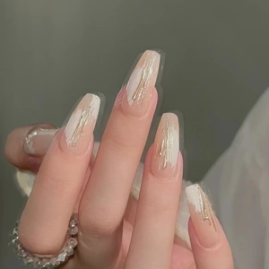 Macro detail of long coffin nails with nude pink base, gold wire art and white strokes
