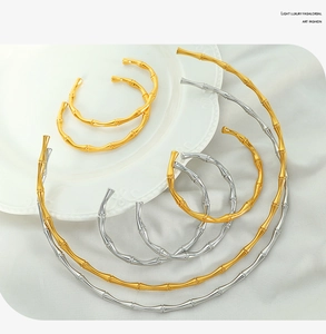 Chic gold and silver bamboo shaped collars and bracelets displayed on ceramic