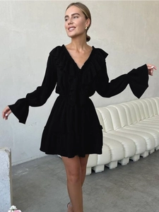 Detail view of the elegant ruffled V-neckline and bell sleeves on this black chiffon dress