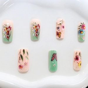 Pastel gradient press-on nails featuring floral and butterfly designs on a white tray
