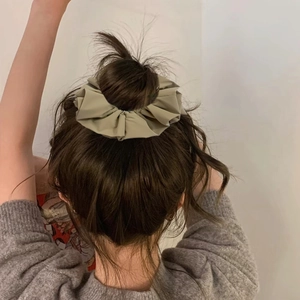 Olive green faux leather pleated hair scrunchie shown on a model's ponytail