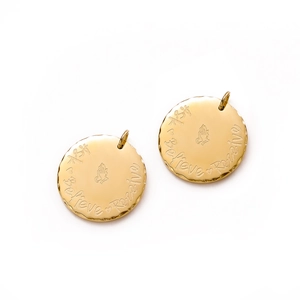 Dettaglio di ciondoli circolari in oro 14K con citazioni incise e simboli spirituali