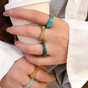 Five-piece colorful acrylic wave ring set shown in a natural lifestyle hand setting