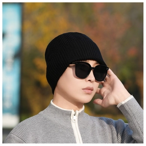 Close-up of a black ribbed knit beanie showing tight vertical stitching and snug fit