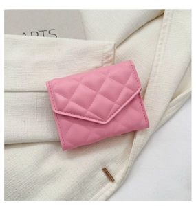 Detailed close-up of a pink quilted PU leather envelope card holder on white fabric