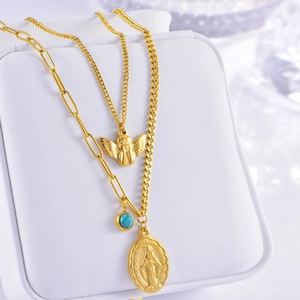 Close-up of vintage gold layered necklaces with angel medal and turquoise bead detail