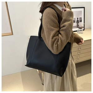 Chic black PU leather tote bag worn by a model in a cozy, minimalist indoor setting