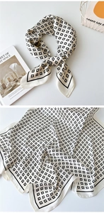 Detailed view of cream silk scarf with black geometric G-pattern and satin finish